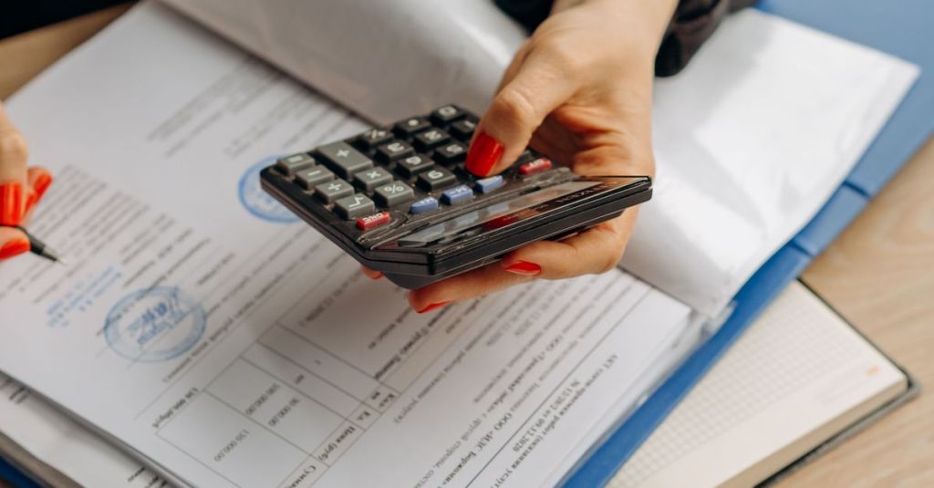Person using calculator and documents for accounting tasks in an office setting.